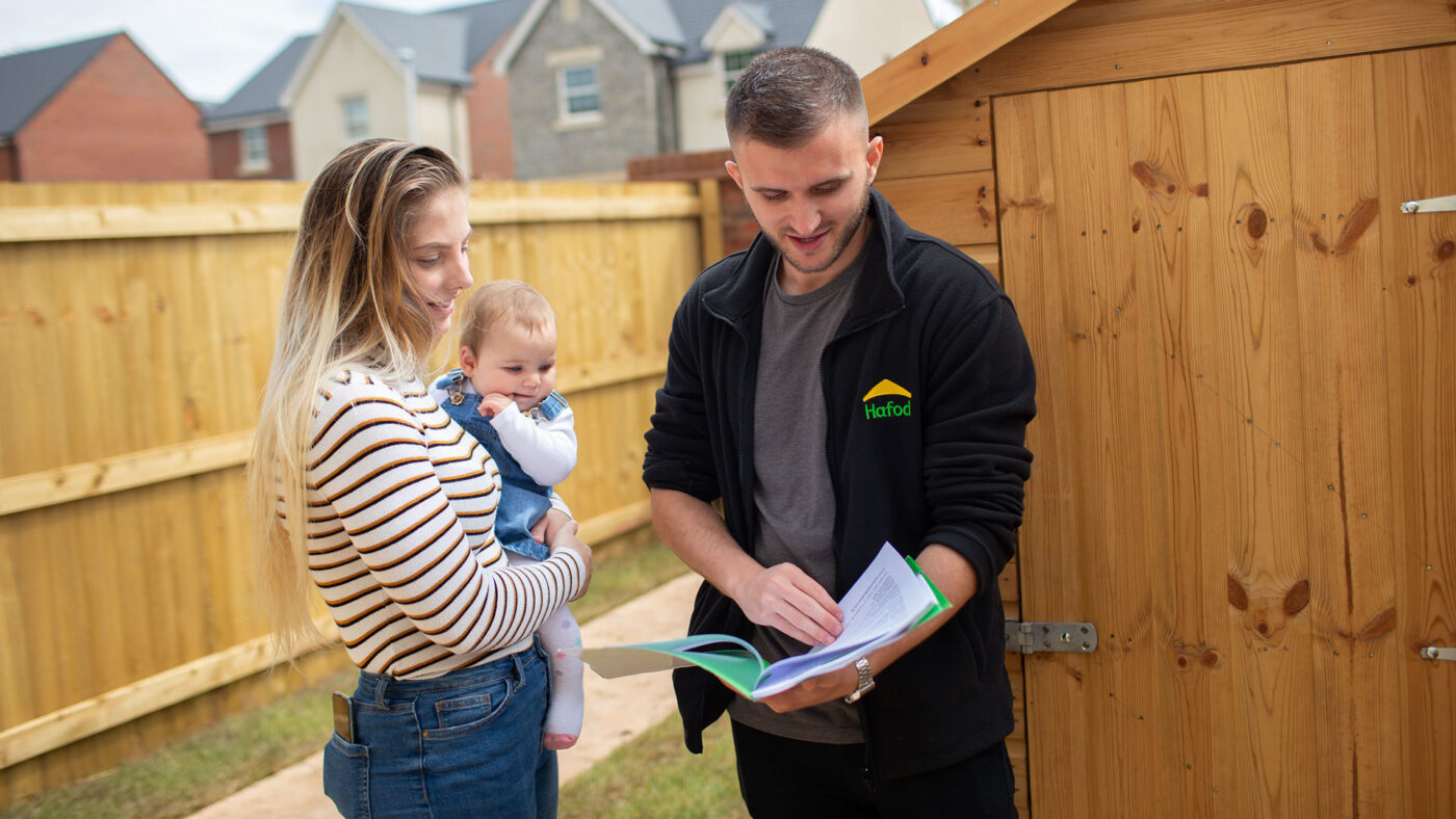 Housing association staff member reading house information booklet to new tenant and baby